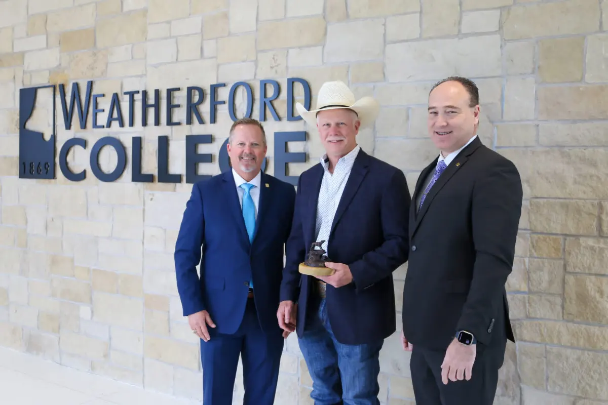 Brent Gough poses in front of a sign for Weatherford College, one of the community organizations Gough Wealth Management helps